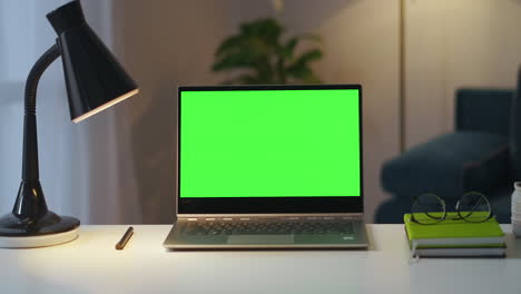 working-place-of-writer-or-freelancer-in-apartment-laptop-with-green-screen-for-chroma-key-books-and-lamp-on-table-static-shot-in-home-office